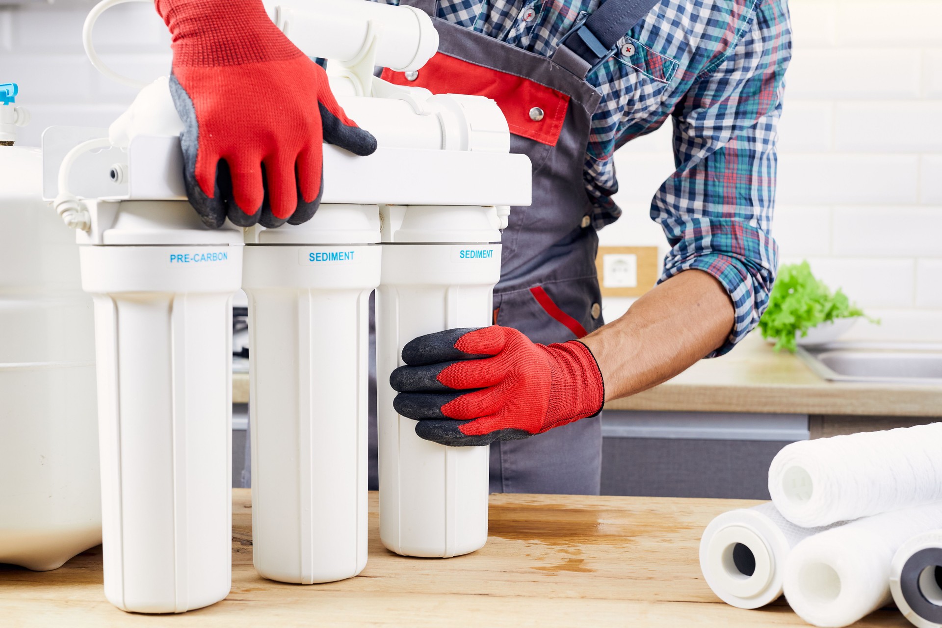 Plumber installs or change water filter. Replacement aqua filter. Repairman installing water filter cartridges in kitchen. Installation of reverse osmosis water purification system.
